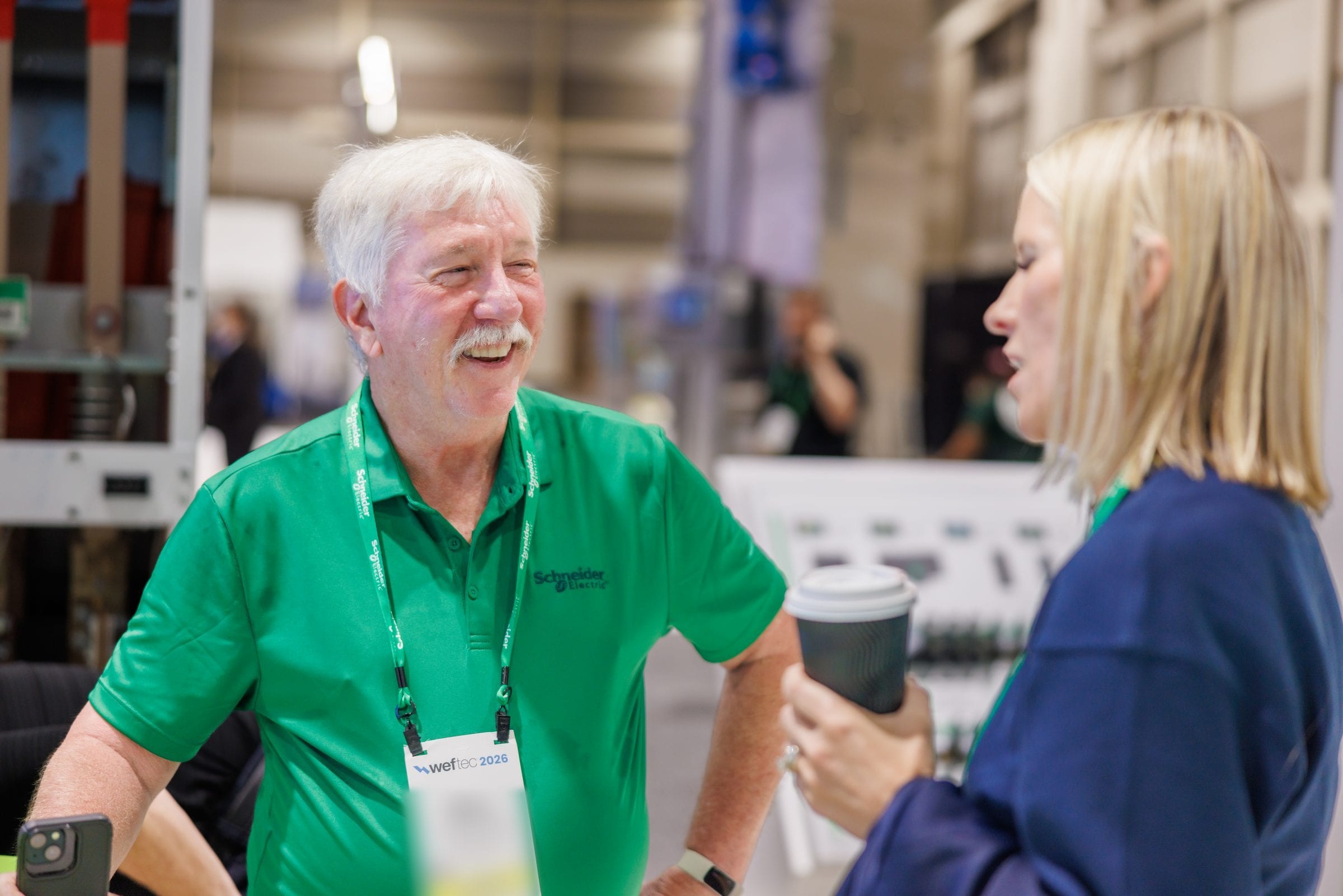Schneider Electric team member sharing a laugh at the WEFTEC 2026 booth